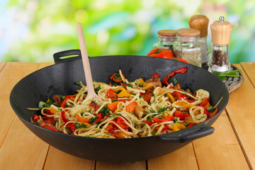 Noodles with vegetables on wok on nature background background