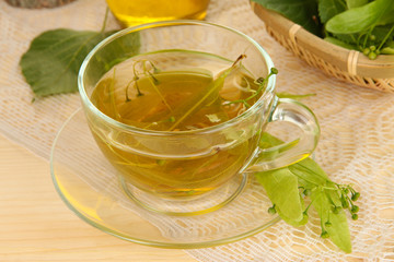 Glass cup of tea with linden on wooden table close-up