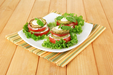 Tasty roasted marrow and tomato slices with salad leaves,