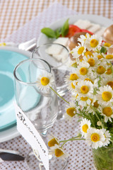 Table setting with chamomiles on checkered tablecloth