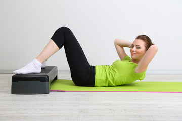 Beautiful young woman exercises on stepper