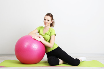 Fototapeta na wymiar Portrait of beautiful young woman exercises with gym ball