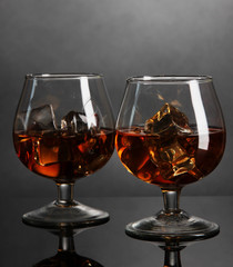 Brandy glasses with ice on grey background