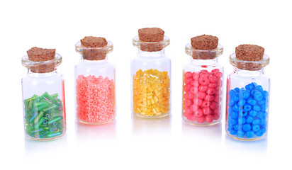 Different colorful beads in bottles isolated on white