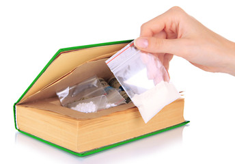 Hand holding narcotics near book-hiding place isolated on white