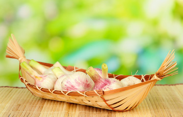 Fresh garlic in wicker basket, on bright background