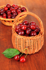 Fototapeta na wymiar Cherry berries in wicker baskets on wooden table close-up
