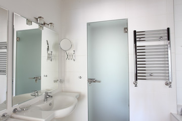 Sink, mirrors and heated towel rail in bathroom.