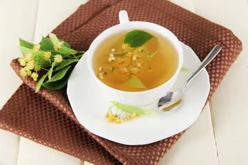 Cup of tea with linden on napkin on  wooden table
