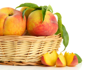 Ripe sweet peaches with leaves in basket, isolated on white