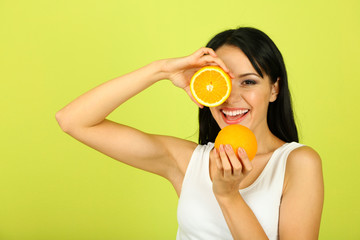 Girl with fresh juice and orange on green background