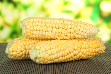 Fresh corn on bamboo mat, on bright background