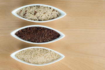3 bowls of raw rice; brown, red, and mixed rice from top view