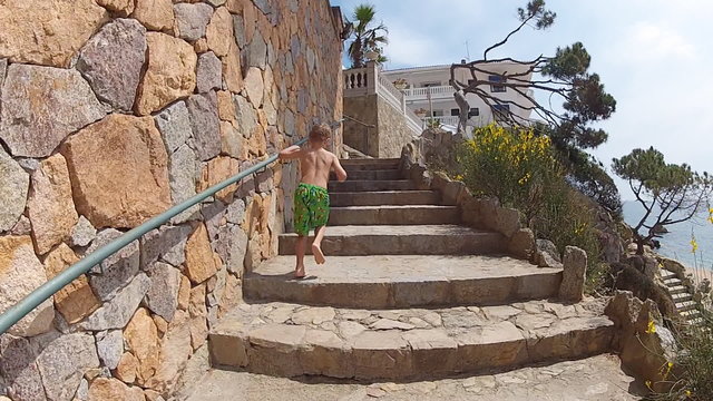 boy runs up the stairs along the seashore