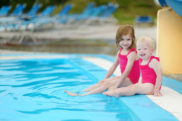 Fototapeta na wymiar Two sisters sitting by a swimming pool