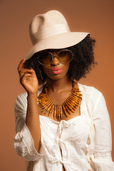 Retro 70s fashion afro woman with sunglasses and white hat. Brow