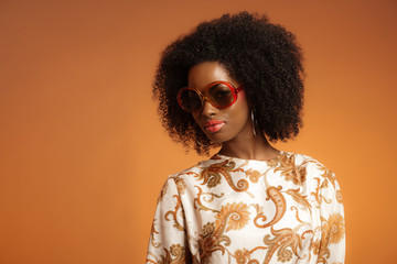 Retro 70s fashion african woman with paisley dress and sunglasse