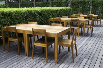 Fototapeta na wymiar Drewniane stoły w bujnym ogrodzie