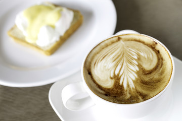 Coffee in a white ceramic cup with egg benedict for breakfast