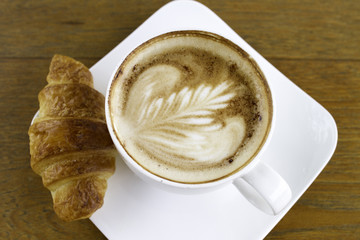 Coffee in a white ceramic cup and croissant