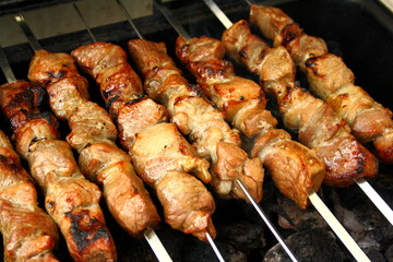 Marinated lamb grilling on metal skewer, close up