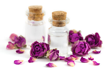 Fototapeta na wymiar Dwie butelki wypełnione olejem zapachu róży i suszone pąki róży