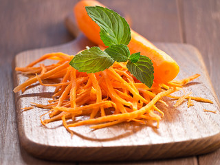 Möhren Julienne mit einer Möhre auf einem Holztablett