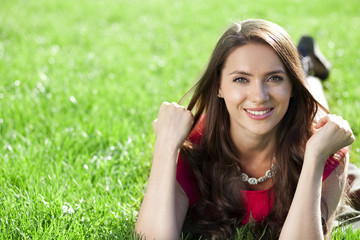 Naklejka premium Portrait of young woman lying on a green lawn