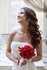 Portrait of happy bride posing with red bouquet