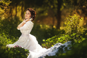 Gorgeous brunette beauty in a old-fashioned dress in a forest