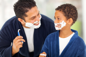 playful father and son shaving together