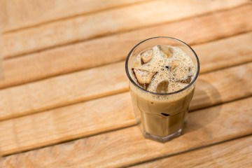 Cold ice coffee with cubes on wooden table