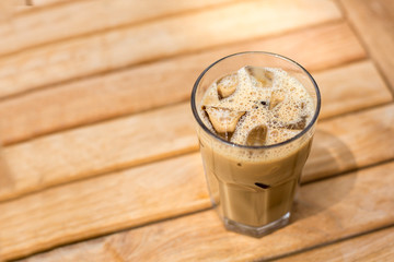 Cold ice coffee with cubes on wooden table