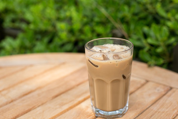 Cold ice coffee with cubes on wooden table