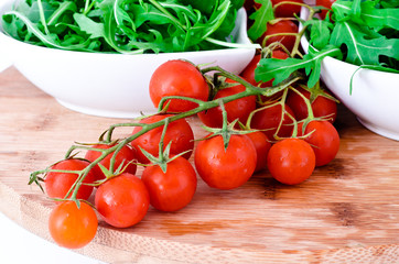 tomatoes and  rucola  in white cups over wooden board