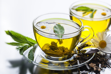 Cup with green tea and green leaves.