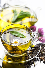 Cup with green tea and green leaves.