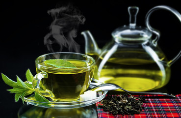 Cup with green tea and green leaves.