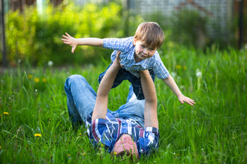 Fototapeta premium Father and son playing lying on the grass in the park