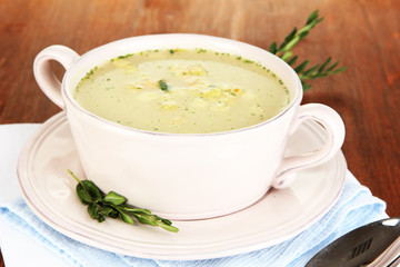 Nourishing soup in pink pan on wooden table close-up