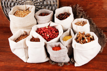 Different kinds of beans in sacks on wooden background