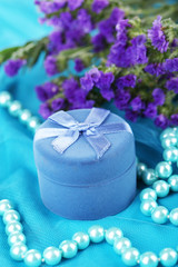 Flowers  and engagement ring box on blue cloth