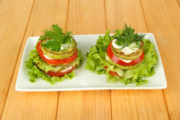 Tasty roasted marrow and tomato slices with salad leaves,