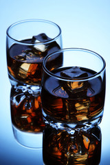 Brandy glasses with ice on blue background