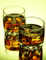 Brandy glasses with ice on green background
