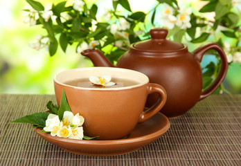 Cup of tea with jasmine, on bamboo mat, on bright background