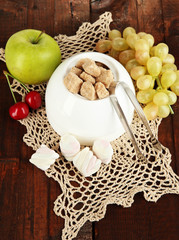 Unrefined sugar in white sugar bowl on wooden background