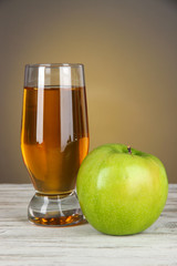 Glass of fresh apple juice on table on gray background