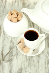 Cup of coffee, teapot and sugar-bowl on color wooden background