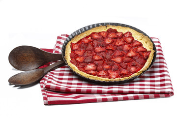 Strawberry tart on checkered red and white table cloth isolated